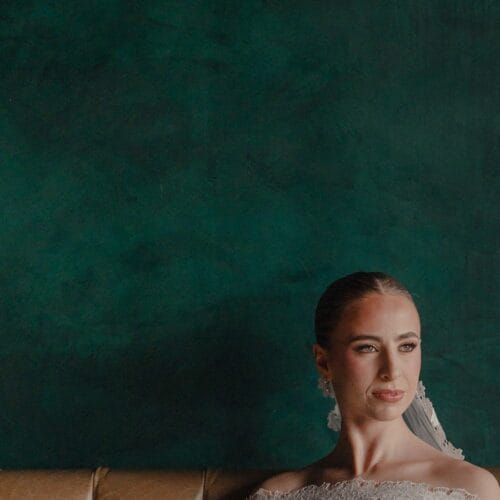 Retrato de una novia sentada frente a una pared verde oscuro